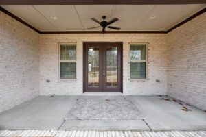 A front porch with two doors and a ceiling fan.