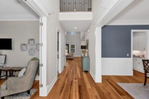 A hallway with hardwood floors and a chair.
