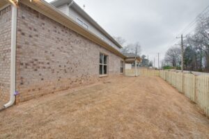 A large brick wall in the middle of an empty yard.